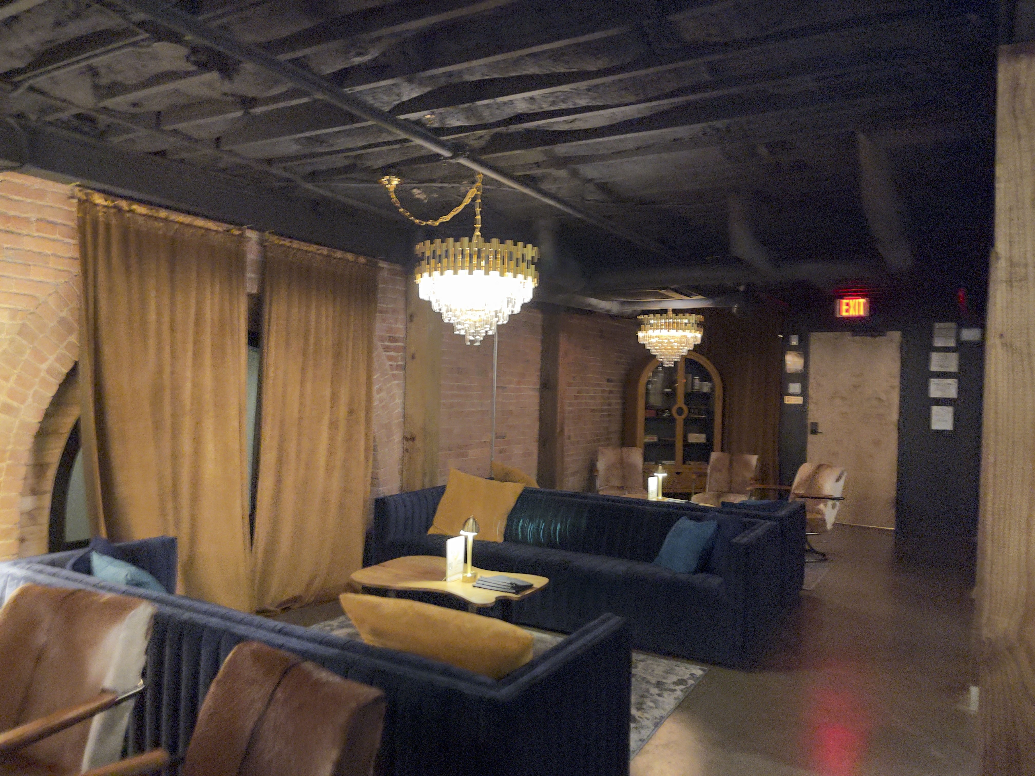 1865 Club lounge with velvet seating, chandeliers, and exposed brick walls.