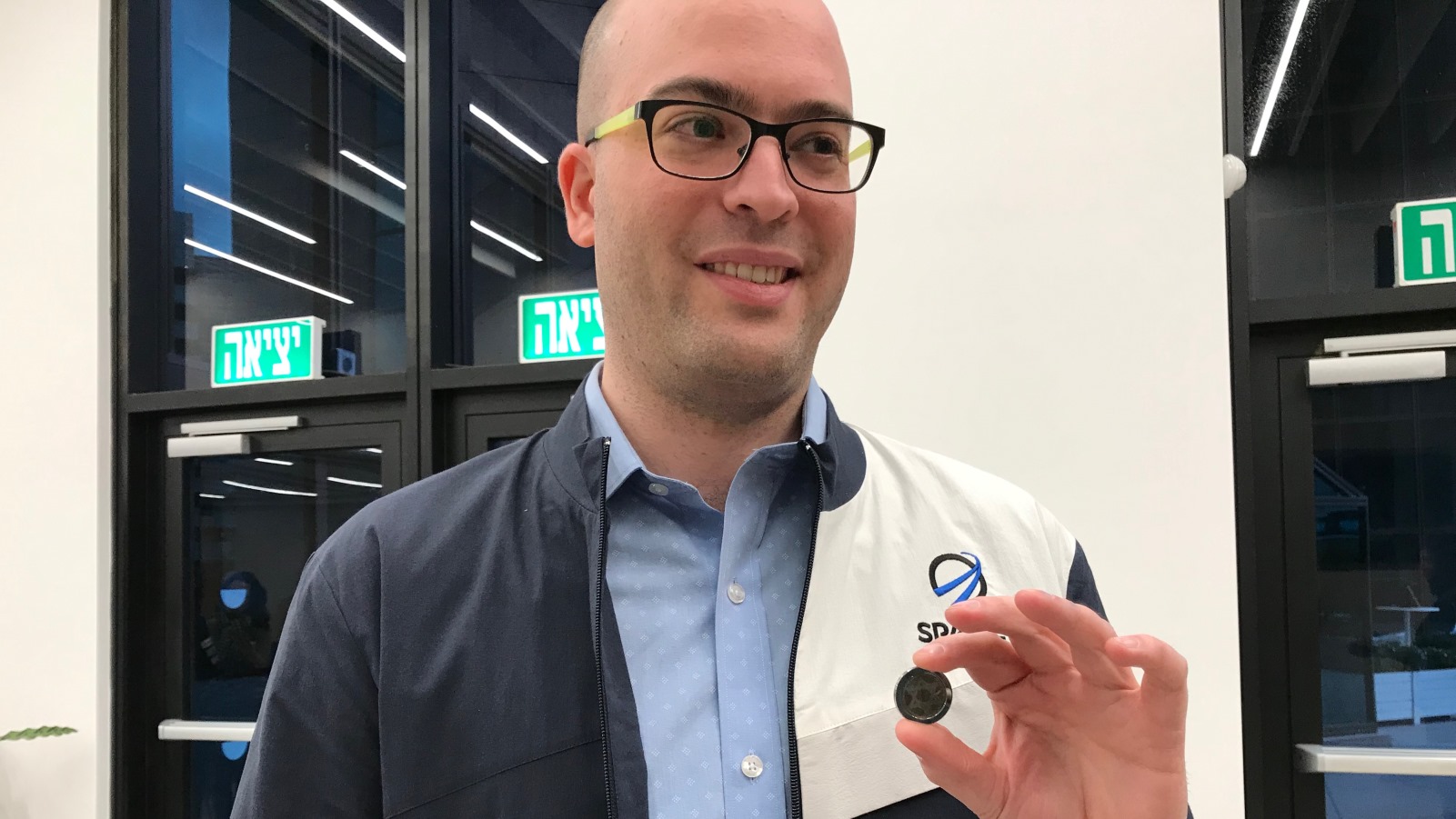 SpaceIL co-founder Yonatan Winetraub, National Institutes of Health award winner, displaying a copy of the coin-size nano Bible in the time capsule aboard Beresheet. (Abigail Klein Leichman)