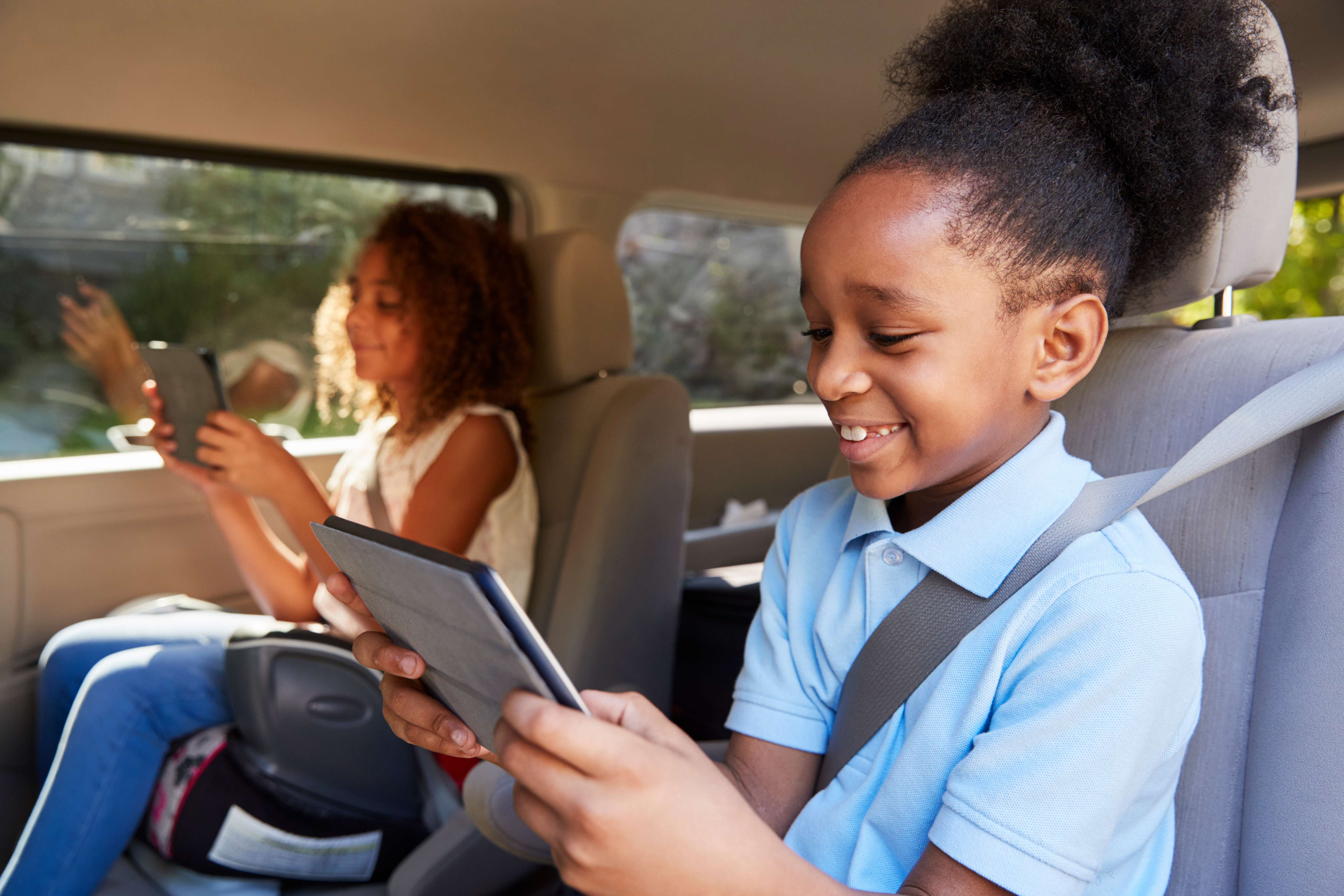 Children Using Digital Devices On Car Journey
