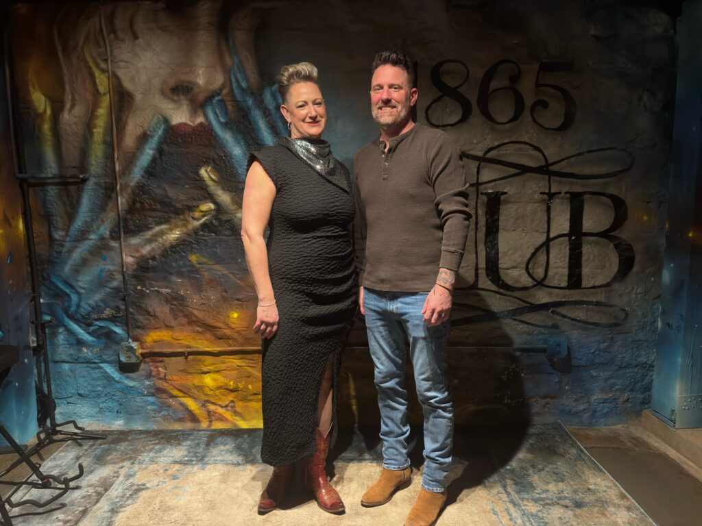 1865 Club owners Carla Waldron and Nick Schroer in front of graffiti mural.
