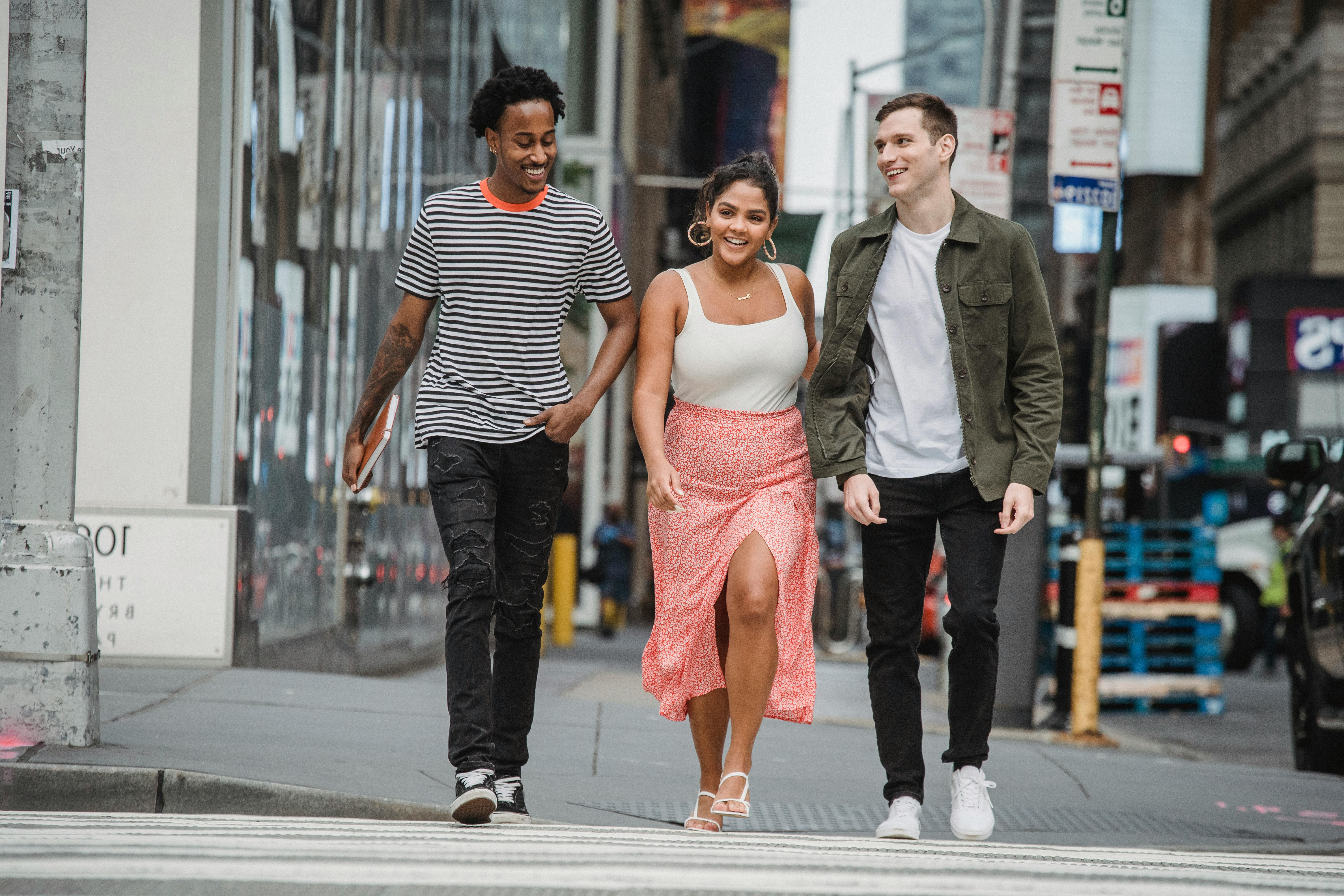 Three people casually walking and laughing together on a city street, embodying the joy of making new friends after moving to Nashville.