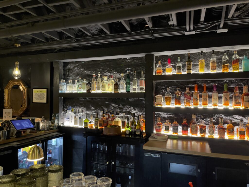 1865 Club bar with backlit liquor shelves and exposed stone walls in Nashville.