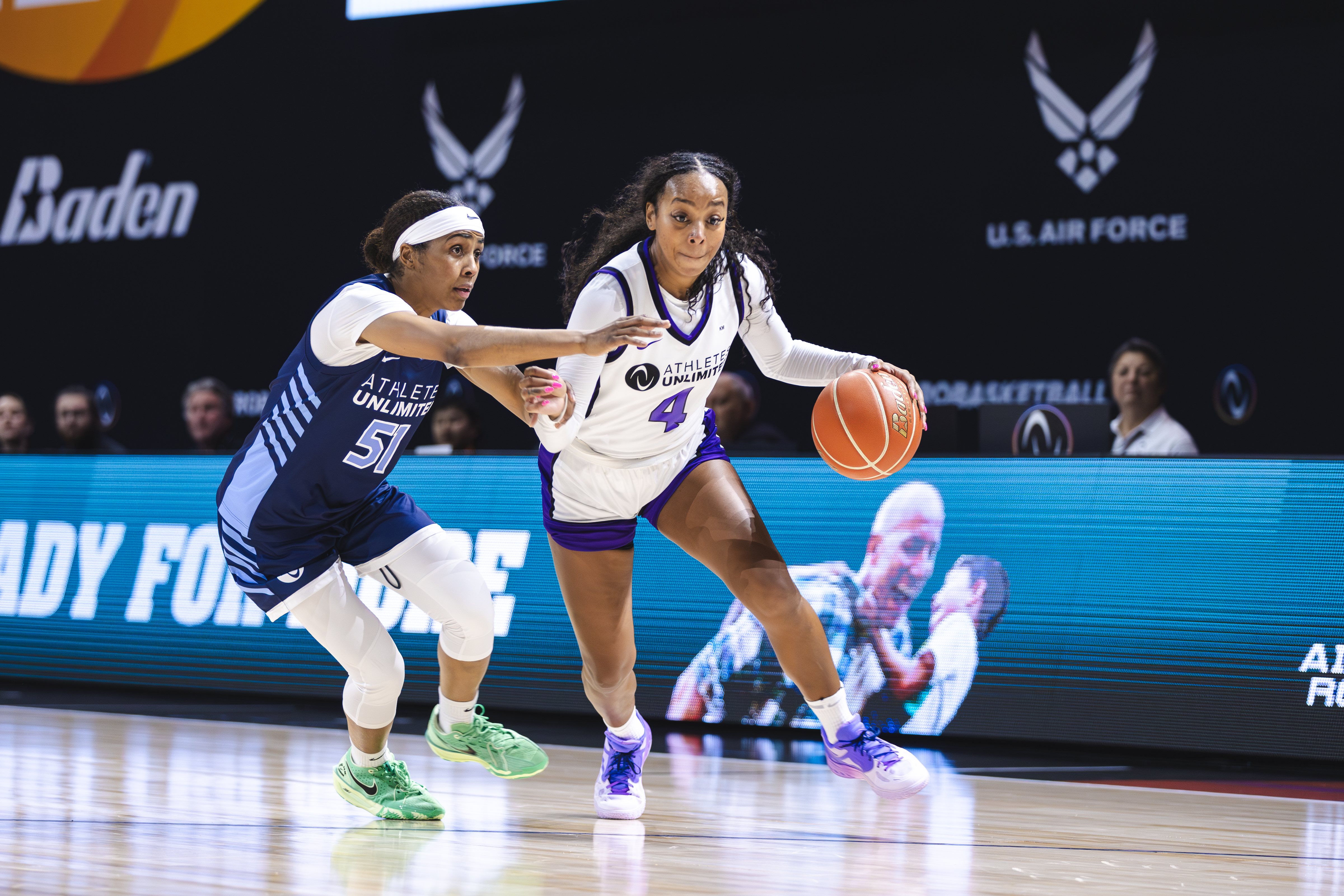 Lexie Brown (#4) of Athletes Unlimited drives to the basket while being defended by an opposing player during a pro basketball game.