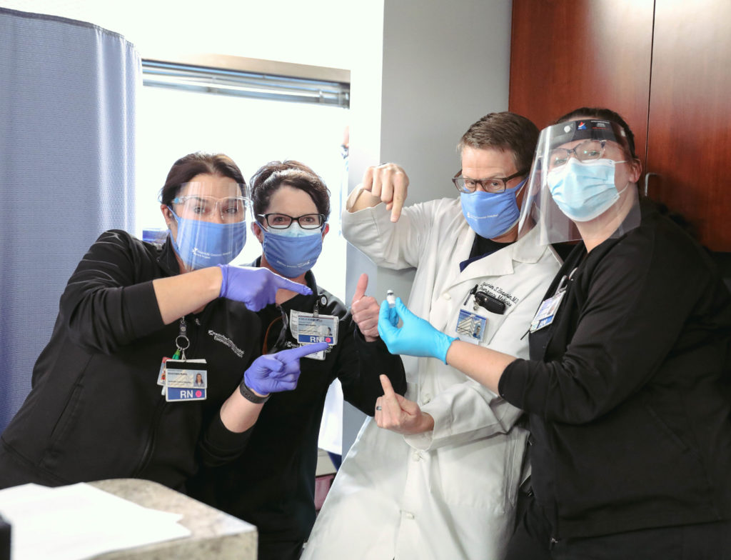 Leslie Horton (RN), Kimila Brogan (RN), Dr. Ben Heavrin (ED), and Ashley Midkiff point at the Pfizer COVID-19 vaccine (Photo by: Carl "C-Roy" Carswell)