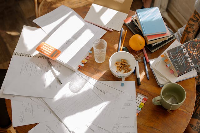An empty cup, books, and papers on a wooden table