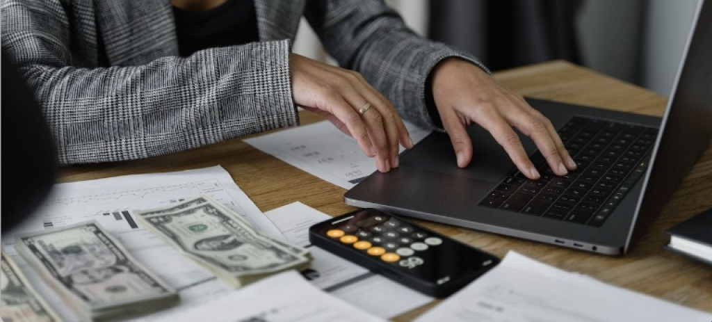 A woman working at a laptop on finances with money on a table