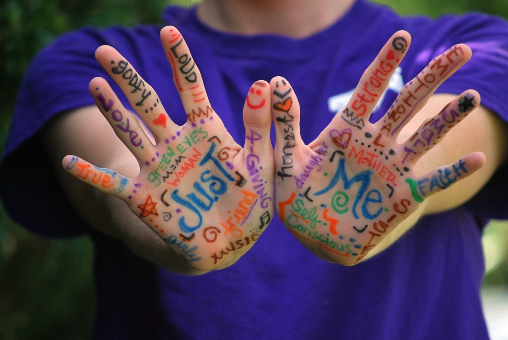 A kid with colorful drawings on his hands.