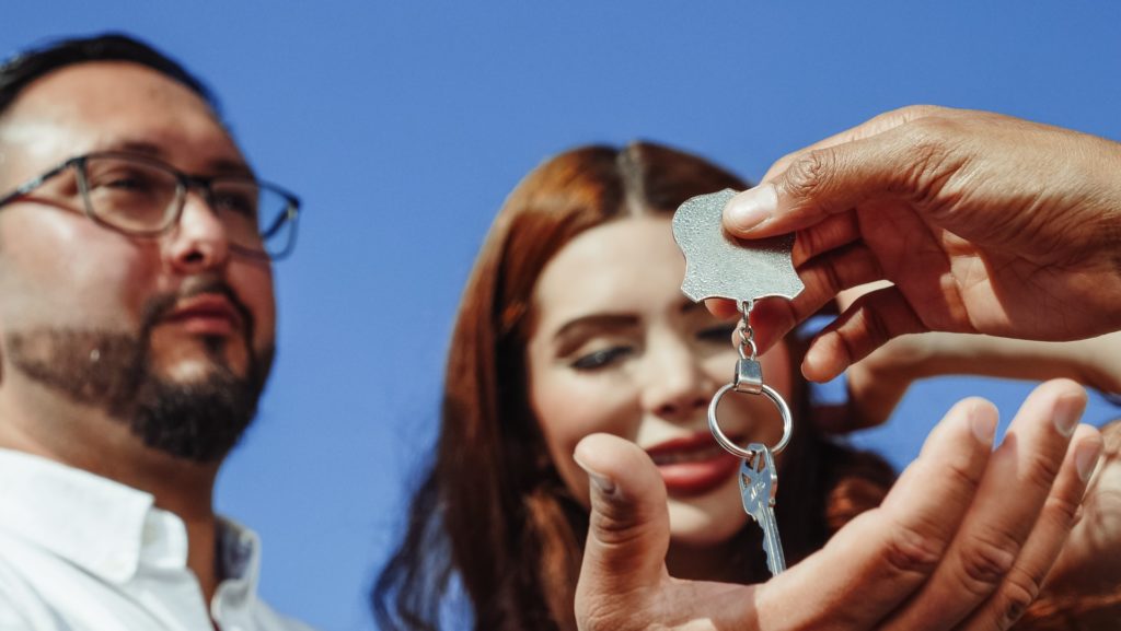 A person giving a house key to buyers