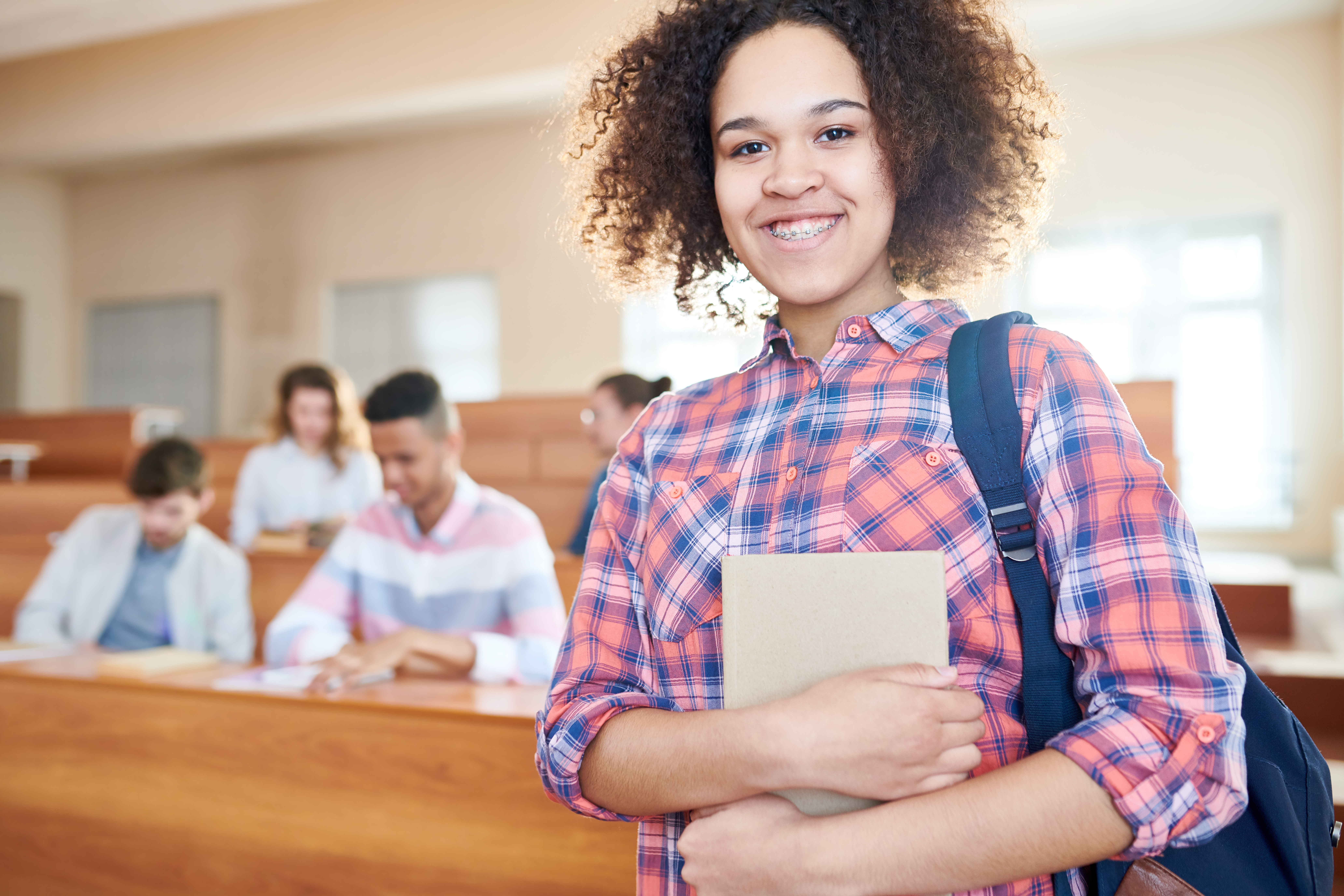Portrait of African American smiling student standing at classroom at university. (Photo by: Seventy Four Images | elements.envato.com)
