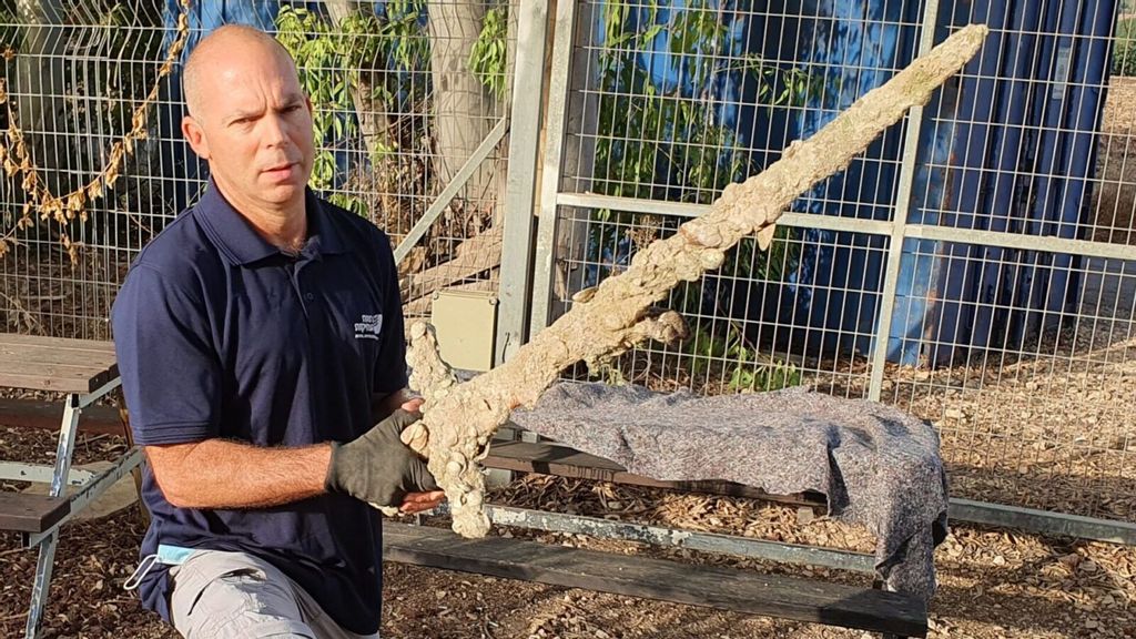 Nir Distelfeld, inspector for the Israel Antiquities Authority, with the Crusader sword.(Anastasia Shapiro/Israel Antiquities Authority)