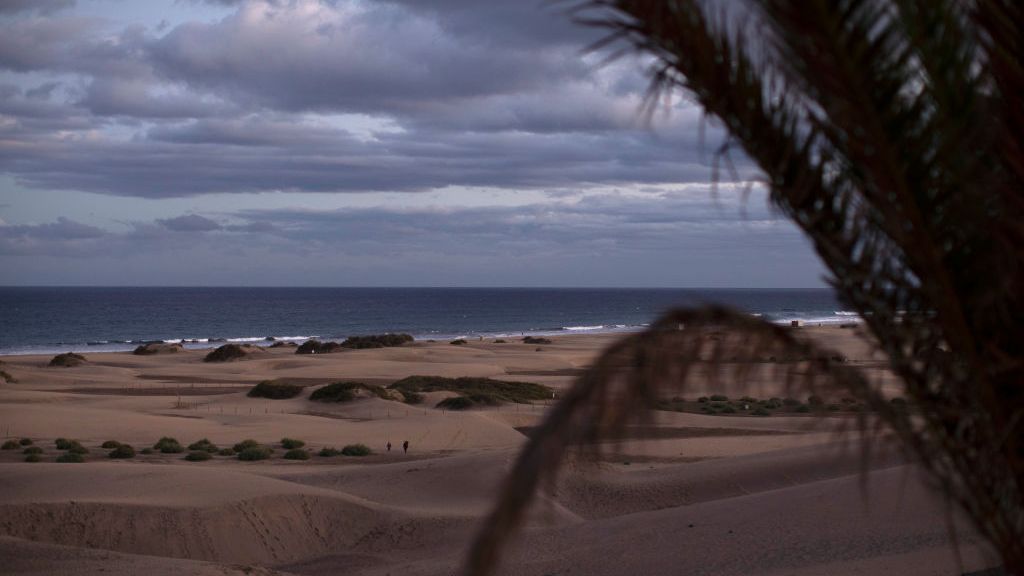 People walk through the sand dunes at sunset on Dec. 5, 2020, in Maspalomas, Spain. The dunes at Maspalomas saw a positive transformation during the Coronavirus pandemic due to the lack of tourism on the island. Conservation efforts over several years to restore the natural habitat have had a boost due to the lack of disturbance, as many of the dunes have regained their shape and height, and vegetation has started to recover. (Dan Kitwood/Getty Images)
