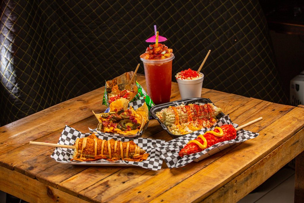 Corn dog and other snacks on the wooden table.
