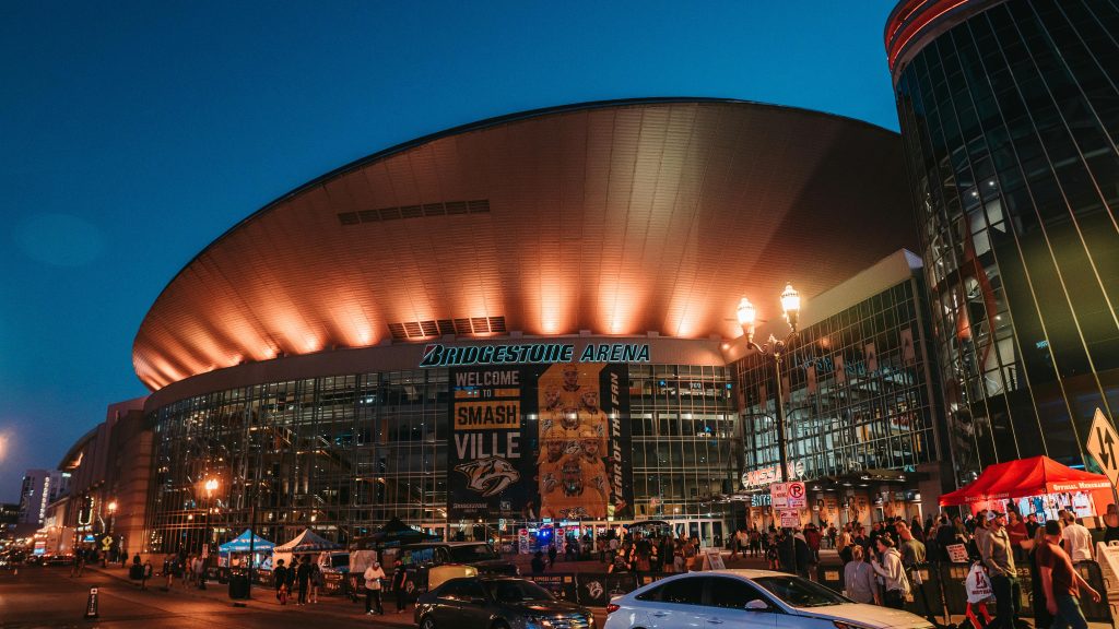 Bridgestone Arena in the evening with a crowd of people outside