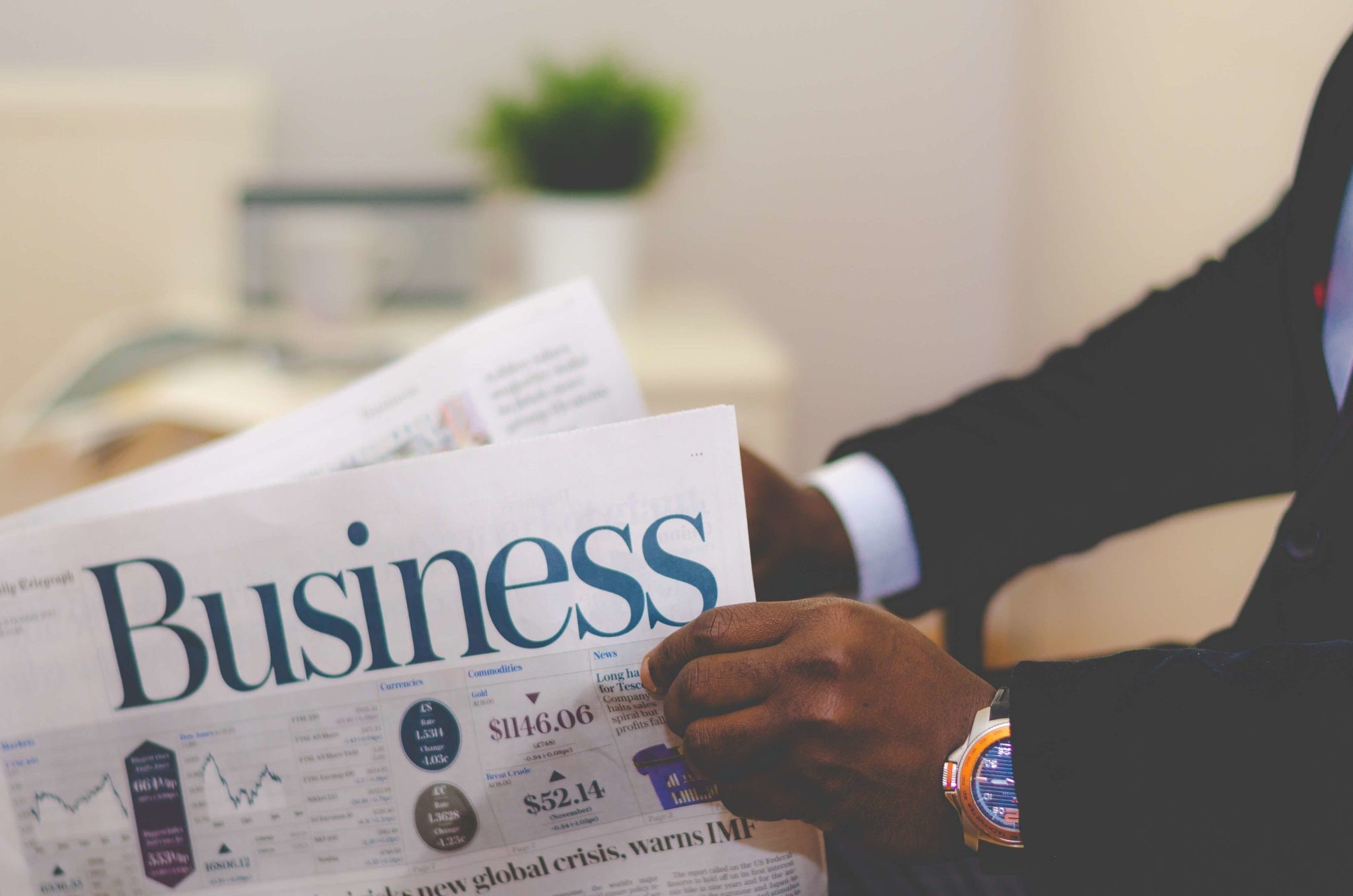 Man wearing a golden watch and reading about steps to take when your business growth stagnates.
