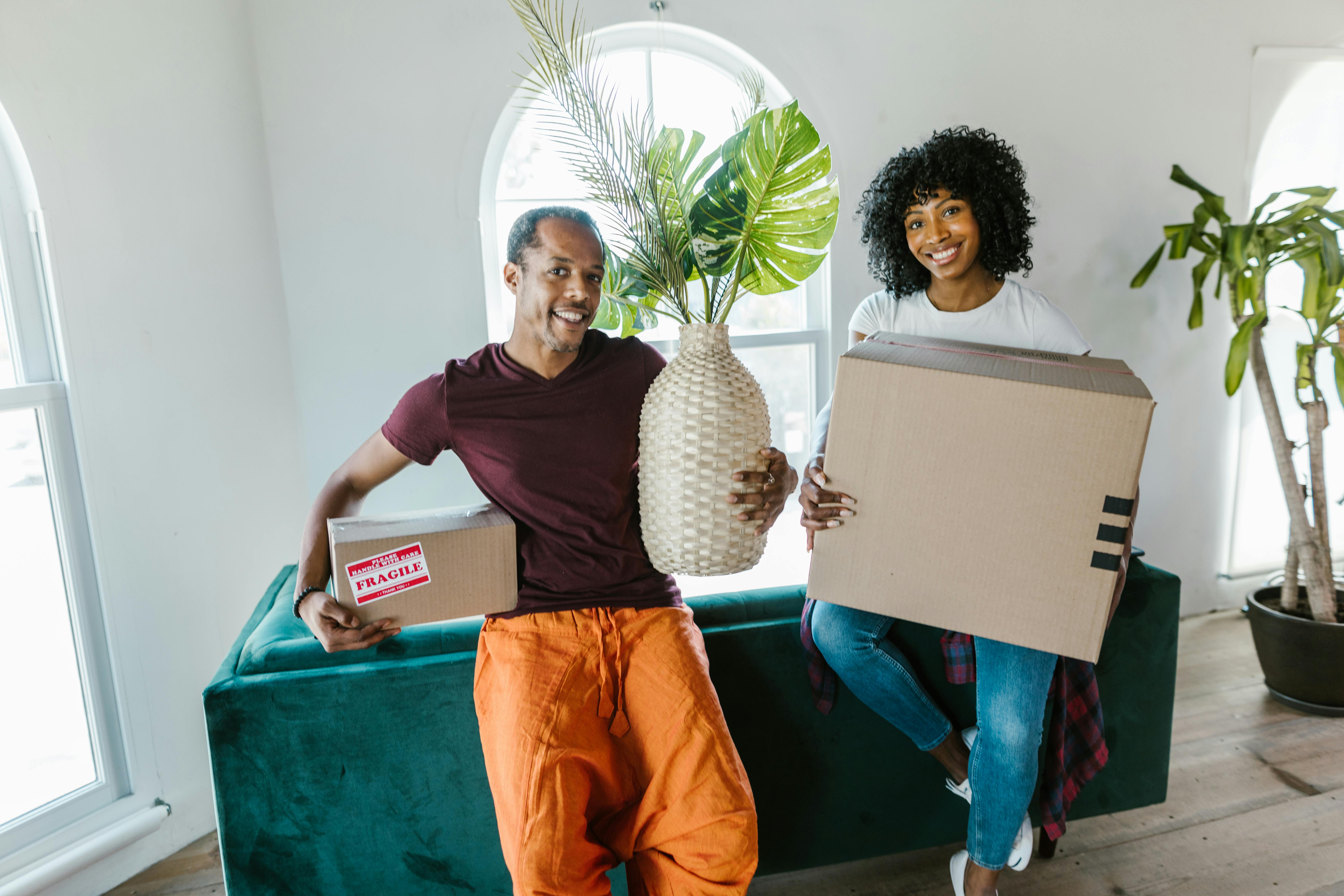 Man and woman holding boxes and a plant