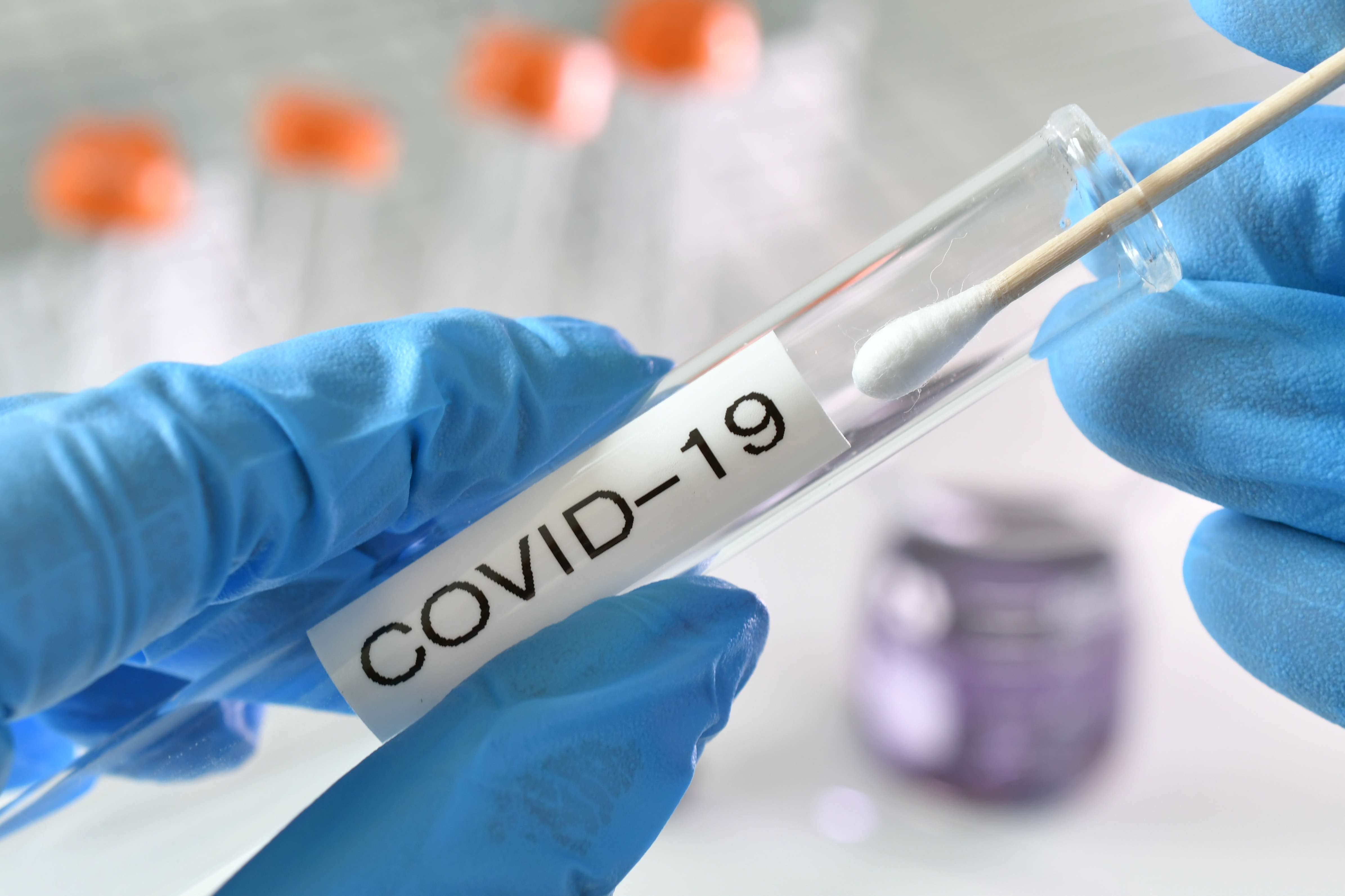Testing swab being inserted test tube labeled Covid-19. (Photo by: Marg Johnson | twenty20.com)